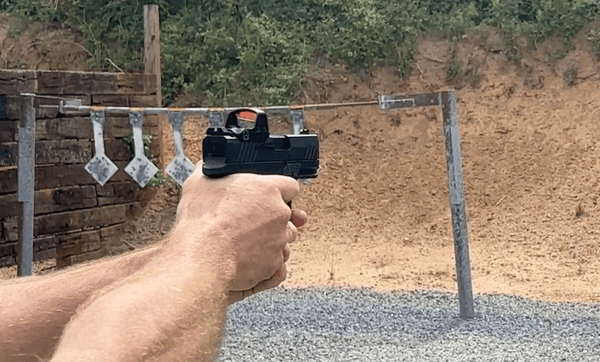 Man shooting pistol with red dot sight